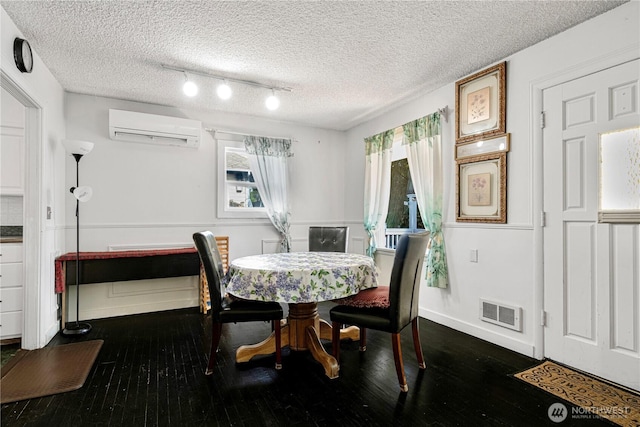 dining room with a textured ceiling, dark wood-style flooring, a wall mounted AC, and visible vents