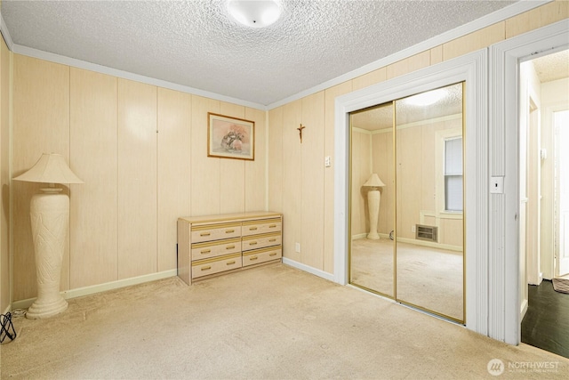 unfurnished bedroom featuring a textured ceiling, ornamental molding, a closet, and carpet flooring