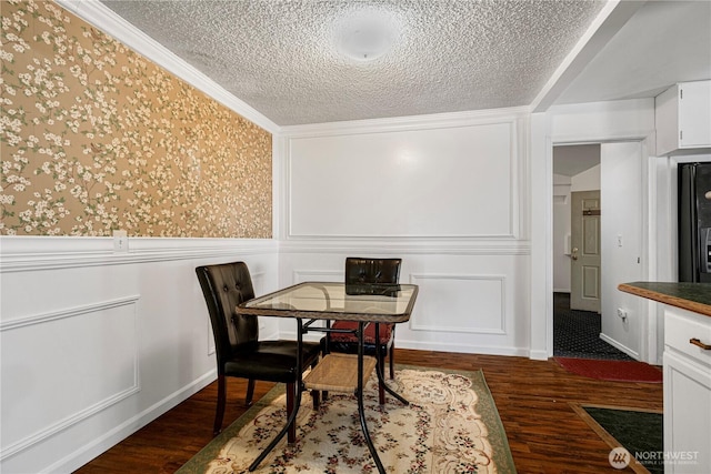 dining room featuring dark wood finished floors, a textured ceiling, and a decorative wall