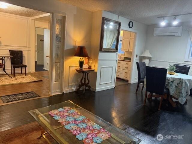 interior space with dark wood finished floors, a textured ceiling, and a wall mounted AC