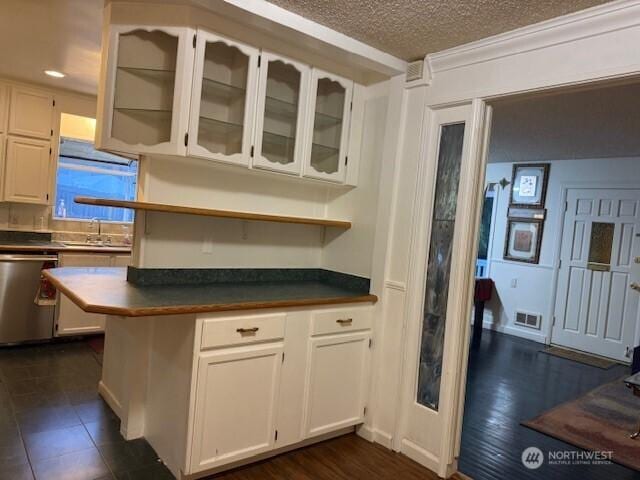 kitchen featuring dark countertops, visible vents, dishwasher, white cabinetry, and a sink