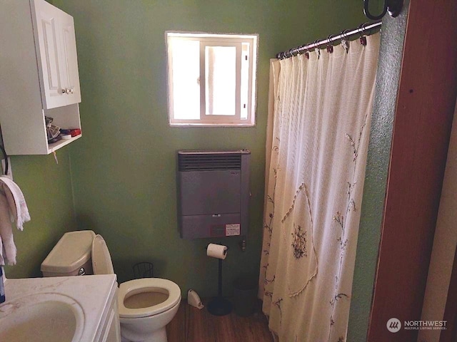 bathroom with hardwood / wood-style floors, vanity, a shower with shower curtain, toilet, and heating unit