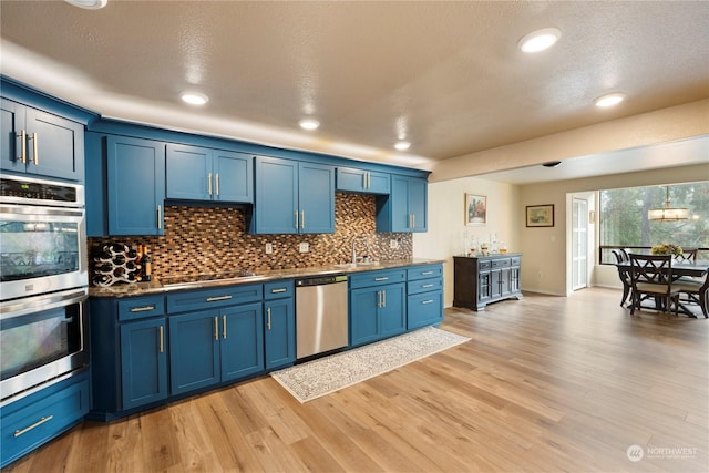 kitchen with decorative backsplash, appliances with stainless steel finishes, light hardwood / wood-style floors, and blue cabinets