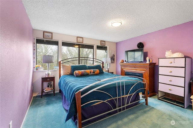 bedroom featuring carpet flooring, a textured ceiling, and a fireplace