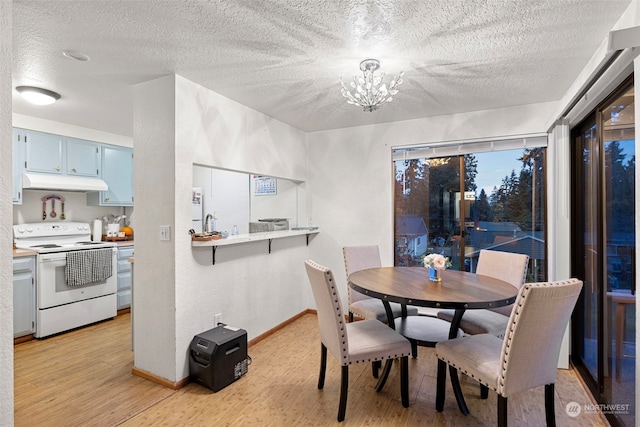 dining space with a textured ceiling, an inviting chandelier, and light hardwood / wood-style flooring