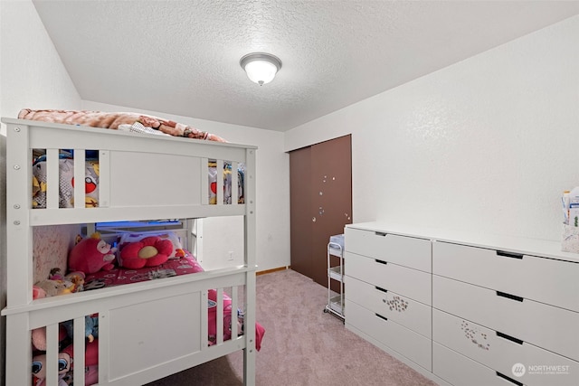 bedroom with light colored carpet and a textured ceiling