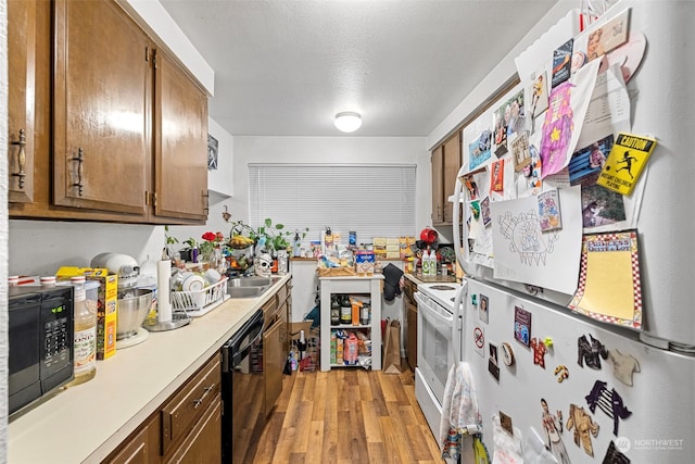 17305 Stone Ct N, Shoreline, WA 98133 - kitchen featuring black appliances, brown cabinetry, light wood-style floors, light countertops, and a textured ceiling