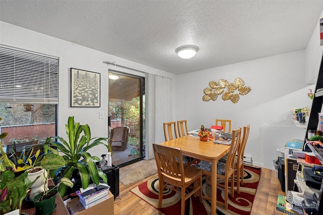 dining area with wood-type flooring and a textured ceiling