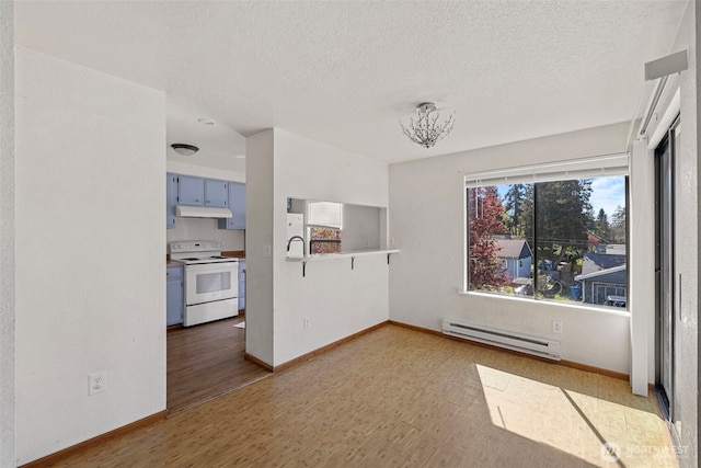 empty room featuring a baseboard heating unit, baseboards, a textured ceiling, and wood finished floors