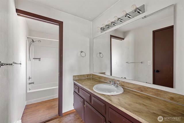 full bathroom featuring  shower combination, baseboards, wood finished floors, and vanity