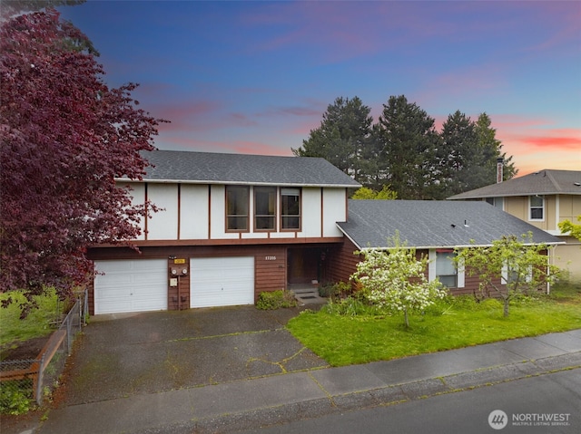 view of front of home with an attached garage, aphalt driveway, board and batten siding, a yard, and roof with shingles