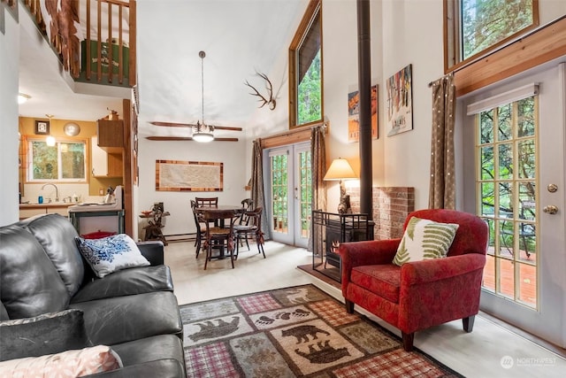 living room featuring french doors, sink, a wood stove, a towering ceiling, and carpet