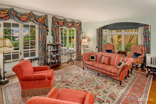 living room featuring wood-type flooring, crown molding, and french doors