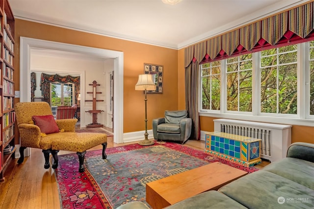 sitting room featuring hardwood / wood-style flooring, plenty of natural light, ornamental molding, and radiator