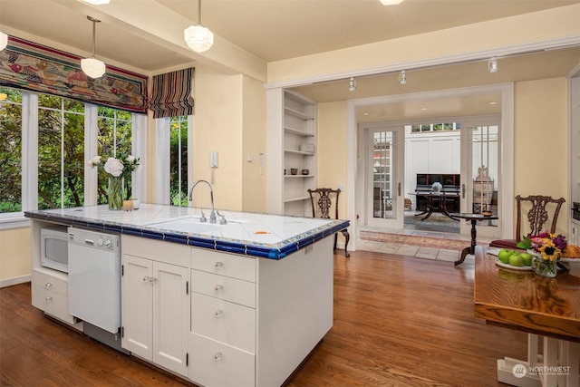 kitchen with pendant lighting, tile countertops, white appliances, white cabinets, and sink