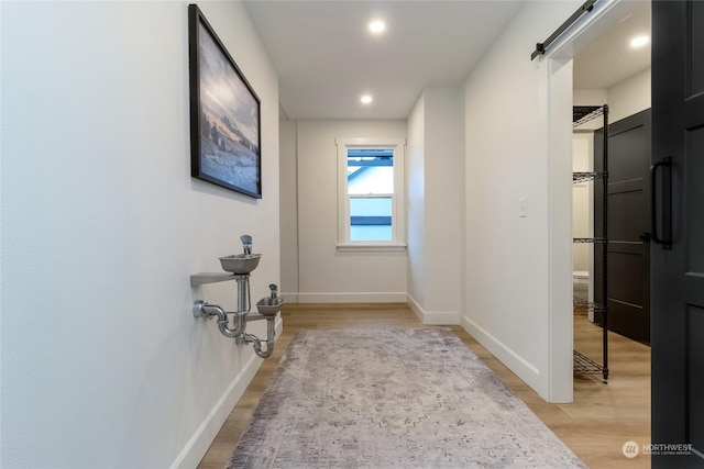 hallway featuring a barn door and light hardwood / wood-style flooring