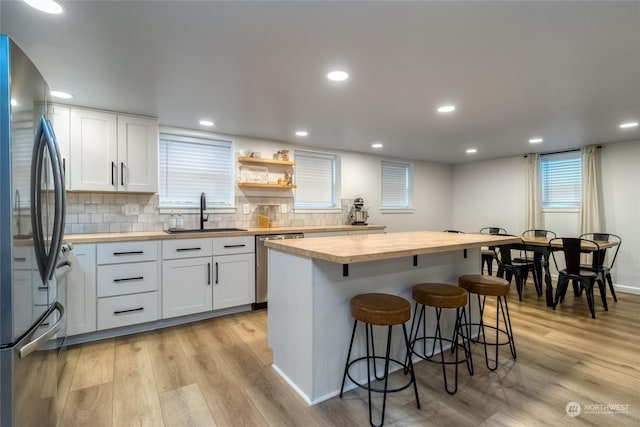 kitchen featuring stainless steel appliances, white cabinetry, sink, and butcher block countertops