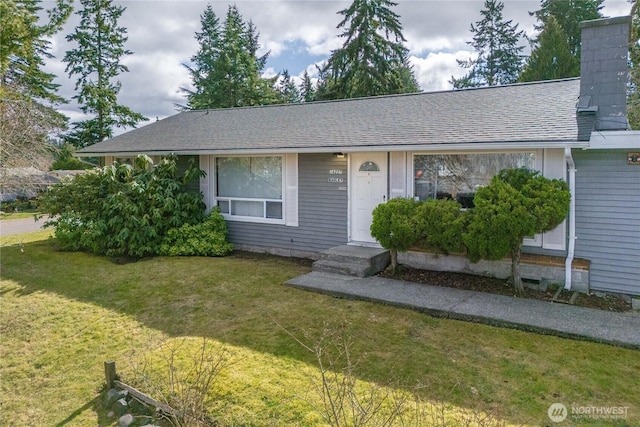 view of front of property with a shingled roof, a chimney, and a front lawn