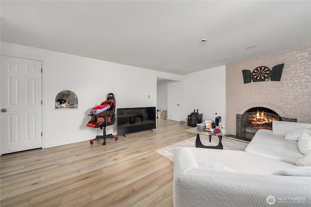 living area with a brick fireplace and wood finished floors