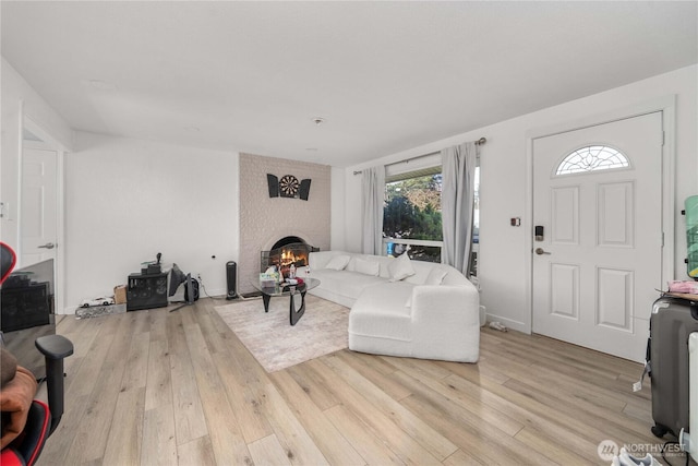 living room featuring light wood-type flooring and a brick fireplace