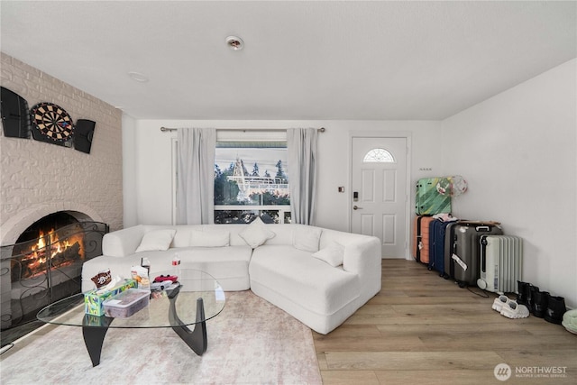 living room featuring a brick fireplace and light wood-style flooring