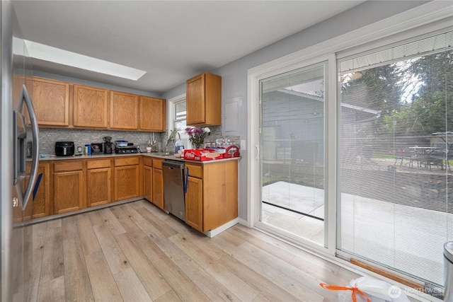 kitchen with stainless steel appliances, light countertops, light wood-type flooring, brown cabinets, and tasteful backsplash