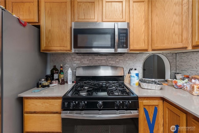 kitchen with appliances with stainless steel finishes, light countertops, and decorative backsplash