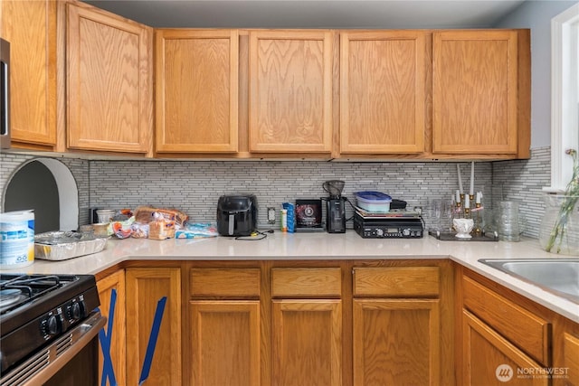 kitchen with a sink, light countertops, and decorative backsplash