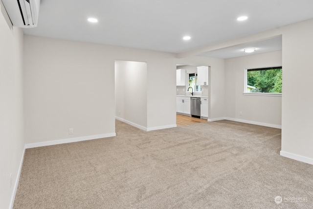 empty room featuring light colored carpet, sink, and a wall unit AC