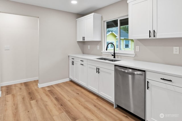 kitchen with stainless steel dishwasher, white cabinets, light wood-type flooring, and sink