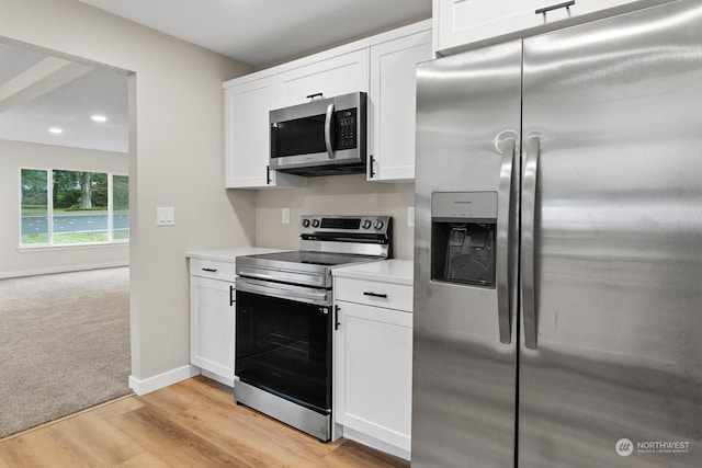 kitchen with stainless steel appliances, white cabinetry, and light hardwood / wood-style floors