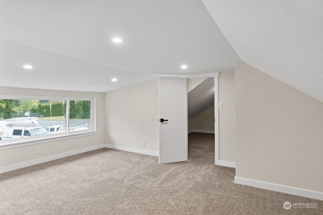 bonus room with light colored carpet and lofted ceiling