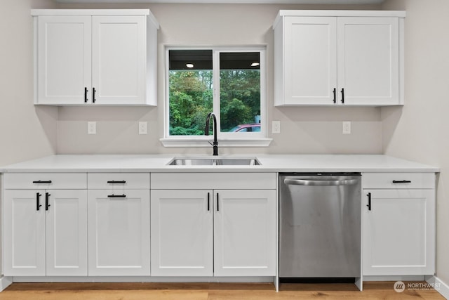 kitchen featuring white cabinets, light hardwood / wood-style flooring, stainless steel dishwasher, and sink