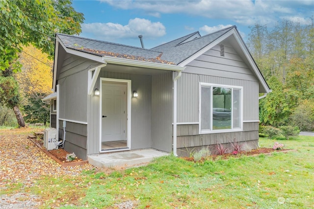 rear view of house with ac unit and a yard