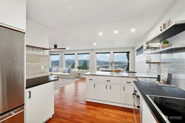 kitchen featuring cooktop, stainless steel refrigerator, white cabinetry, and light hardwood / wood-style floors