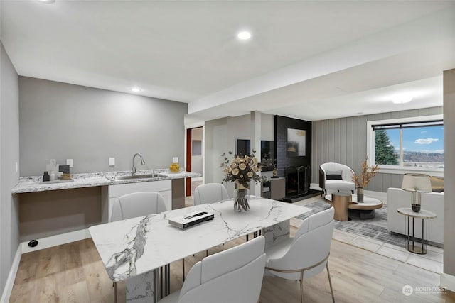 dining space with a fireplace, light hardwood / wood-style flooring, and sink