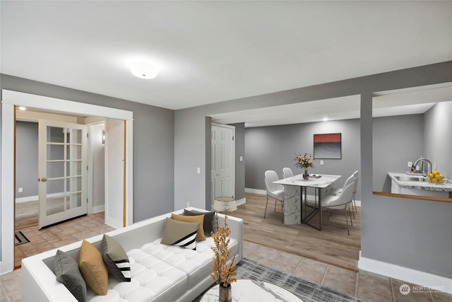 living room with french doors, light wood-type flooring, and sink