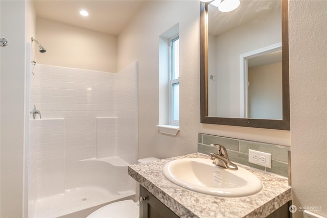 bathroom with backsplash, vanity, toilet, and a shower