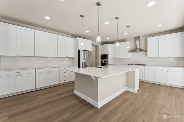 kitchen featuring sink, light wood-type flooring, wall chimney range hood, and stainless steel appliances