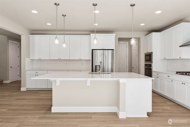 kitchen featuring hanging light fixtures, light hardwood / wood-style floors, an island with sink, and appliances with stainless steel finishes