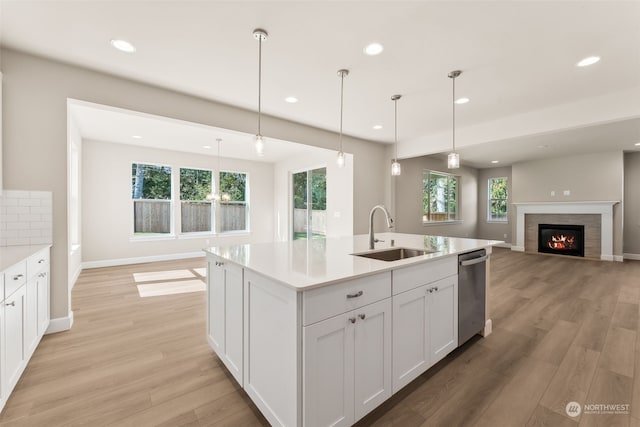 kitchen featuring pendant lighting, light wood-type flooring, white cabinetry, and sink