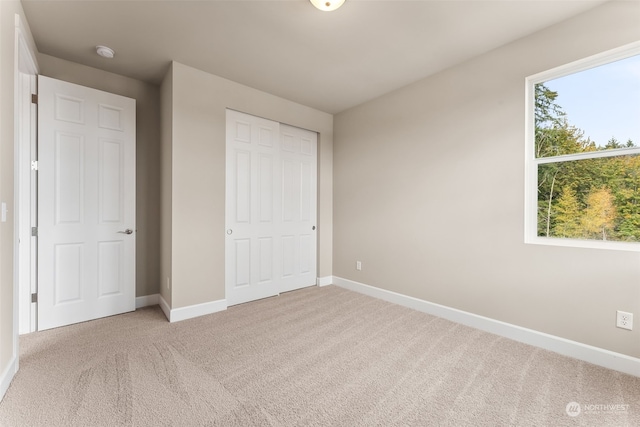 unfurnished bedroom with a closet, light colored carpet, and multiple windows