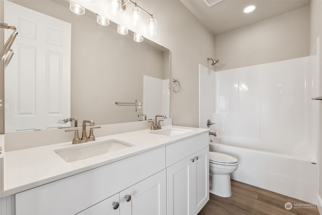 full bathroom featuring hardwood / wood-style floors, vanity, toilet, and shower / tub combination