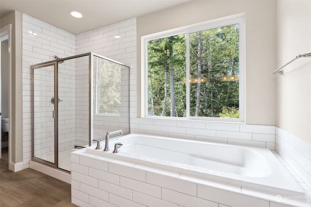 bathroom with independent shower and bath, hardwood / wood-style floors, a healthy amount of sunlight, and toilet