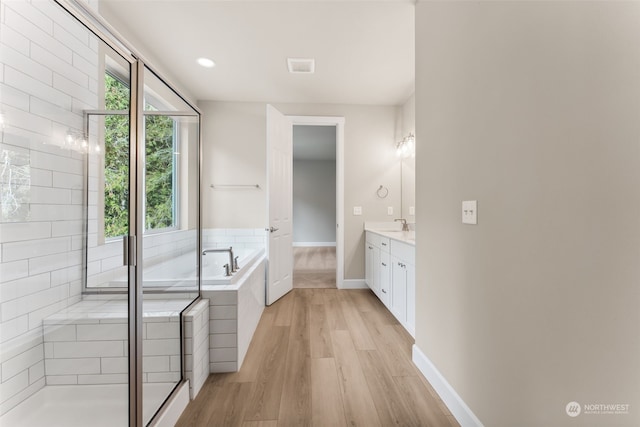 bathroom with plus walk in shower, wood-type flooring, and vanity