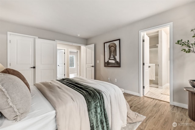 bedroom featuring light wood-type flooring and ensuite bath