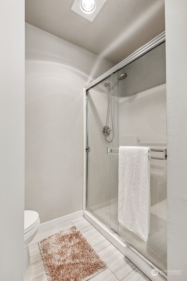 bathroom featuring toilet and a shower with shower door