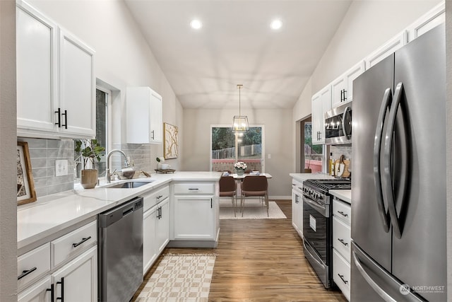 kitchen with white cabinetry, stainless steel appliances, decorative light fixtures, vaulted ceiling, and sink