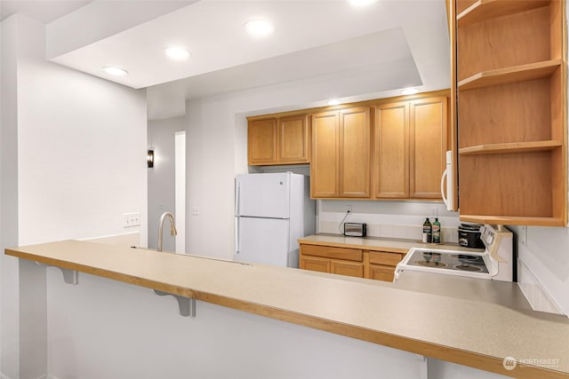 kitchen with kitchen peninsula, white appliances, a breakfast bar area, and sink