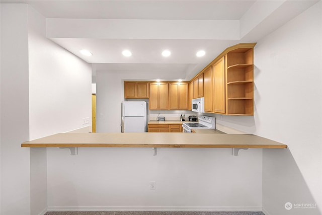 kitchen featuring kitchen peninsula, white appliances, a breakfast bar area, and carpet flooring